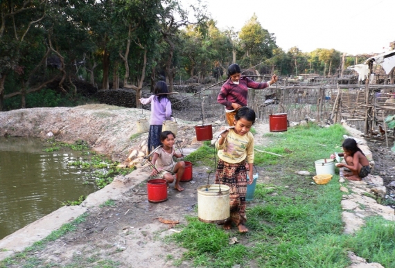 A falu gyermekei a kép szélén lévő kútból, azaz pocsolyából viszik haza a vizet. Kambodzsa a föld egyik legszegényebb országa.